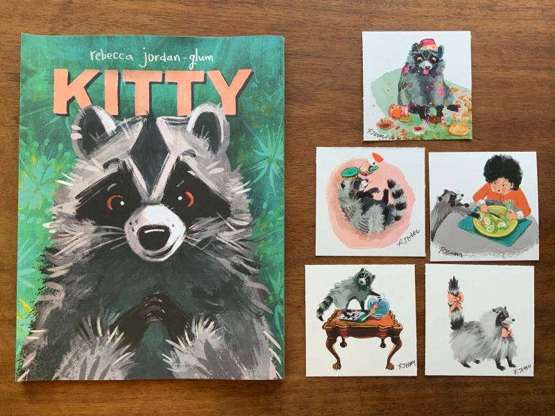 A copy of Kitty on the left hand side next to 5 different art prints. The prints are clockwise from top 1. Kitty raccoon making a large mess eating cupcakes 2. Kitty raccoon trying to steal an egg from Granny’s plate 3. Kitty raccoon freshly groomed with pink bows on its neck and tail 4. Kitty raccoon on ornate wood table trying to catch goldfish in fish bowl 5. Kitty raccoon enjoying being brushed by Granny