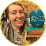 Iz holding a pile of books and a Once Upon A Time mug